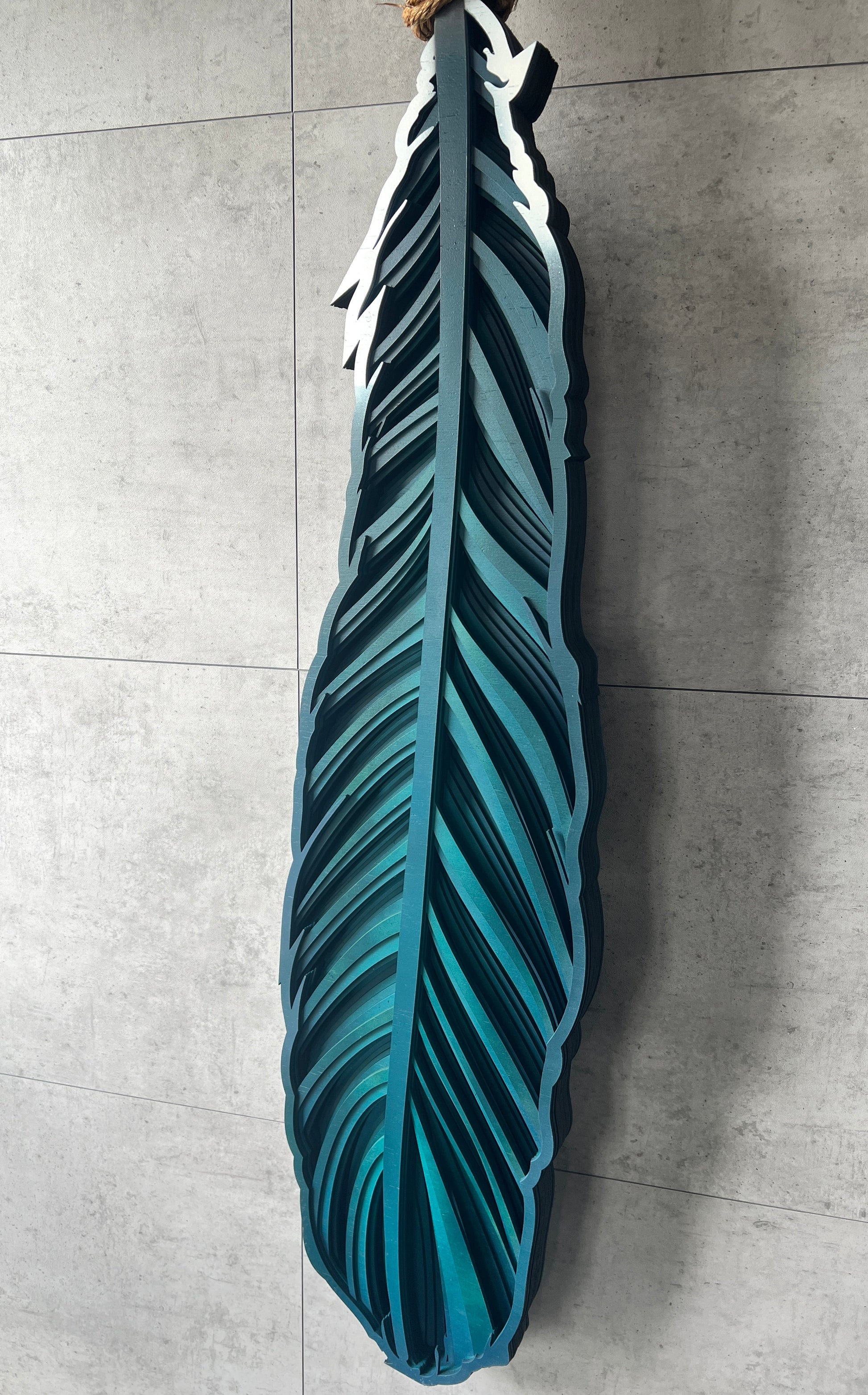 Hanging Tui feather detail showing vibrant colors and rope mounting